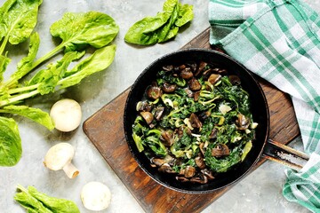 fried champignons with spinach in a pan.
top view. Copy space.