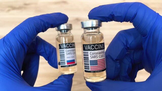 Doctor compare USA and Russian coronavirus vaccine, flags on the labels close-up, vaccination in Europe and America concept 4k footage