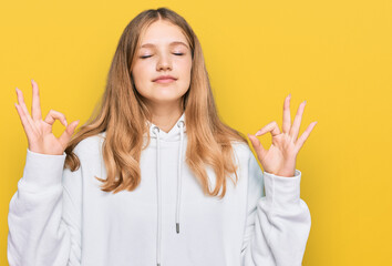 Beautiful young caucasian girl wearing casual sweatshirt relax and smiling with eyes closed doing meditation gesture with fingers. yoga concept.