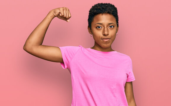 Young african american woman wearing casual clothes strong person showing arm muscle, confident and proud of power