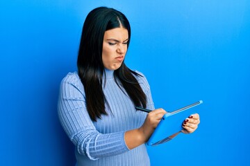 Beautiful brunette woman using touchpad drawing on screen skeptic and nervous, frowning upset...