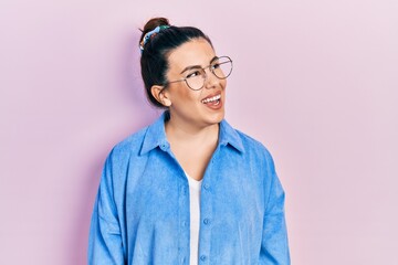 Young hispanic woman wearing casual clothes and glasses looking away to side with smile on face, natural expression. laughing confident.