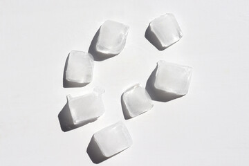 Ice cubes on white background. Top view, copy space. Hard light, shadow