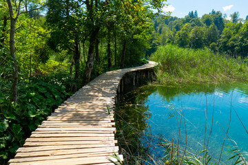Fototapeta na wymiar Croatia. Plitvice Lakes National Park. Walking wooden path along the lake with crystal turquoise water. Popular tourist spot. Listed as a UNESCO World Heritage Site