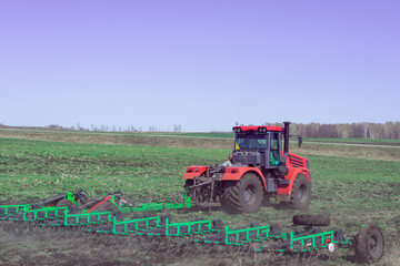 The tractor in the field works with the ground.