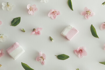 Creative pattern layout made of various spring flowers, leaves and marshmallows. Flat lay nature background.