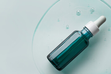 Cosmetic serum bottle sample on cold green blue background