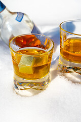 Glasses of cold scotch single malt whisky on white snow