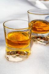 Glasses of cold scotch single malt whisky on white snow