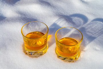 Glasses of cold scotch single malt whisky on white snow