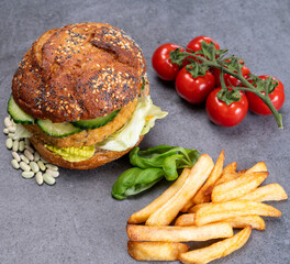 Tasty vegetarian vegan lunch with hamburger made from vegetables based burger, organic bun with seeds and fresh vegetables and french fried potatoes