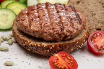 Making tasty vegetarian vegan hamburger from plant based soya beans burger, organic bun with seeds and fresh vegetables