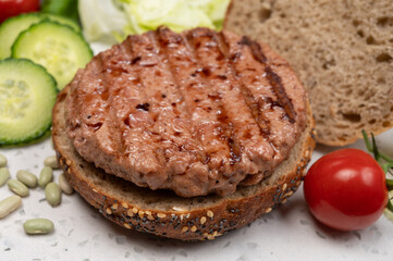 Making tasty vegetarian vegan hamburger from plant based soya beans burger, organic bun with seeds and fresh vegetables