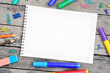 Empty notebook with colorful markers and pencils on a wood table