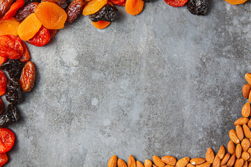 Frame from a mixture of dried fruits and nuts on a gray background. top view.