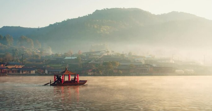 traditional Chinese style boat on river lake with fog misty in the morning sunlight sunrise against village mountain hill on background at Ban Rak Thai village, Mae hong son, Northern Thailand