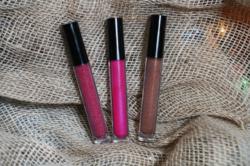   Set of natural lip gloss tube different colours. Lip cream plastic transparent packaging on beige background. Red, wine, pink, beige lipsticks. Lip Gloss Image   - obrazy, fototapety, plakaty
