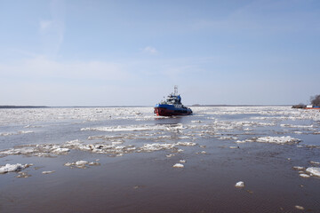 a tugboat sails along a large full-flowing spring river during the ice drift. sunny day,