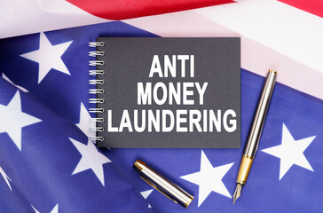 On the table is an American flag, a pen and a notebook with the inscription - ANTI MONEY LAUNDERING