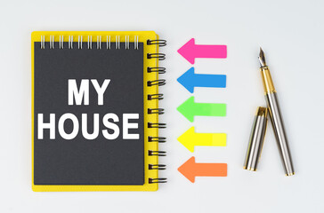 On a white background lies a pen, arrows and a notebook with the inscription - MY HOUSE