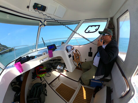 A captain in his boat speaking by radio, walkie-talkie on the sea.
