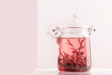 Tea. Pink tea. Drink infused with these rolled leaves. Side view on the teapot, close-up.