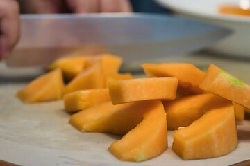 sharp knife chopping through a pile of canteloupe chunks