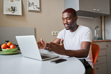 Man looking at the laptop screen with smile while enjoying watching educational webinar