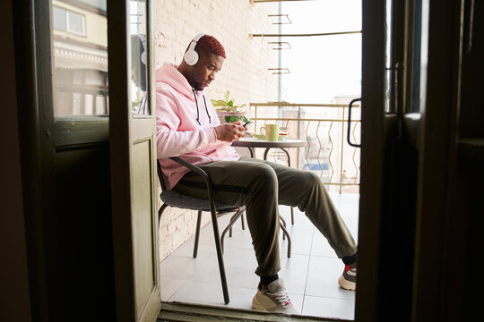 Man Wearing Headset Switches Songs At His Smartphone While Listening Music And Drinking