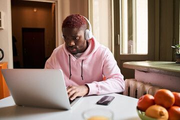 Fototapeta premium Student in headphones looking at the laptop screen while watching online lesson in the kitchen
