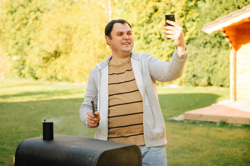 You take a selfie while barbecuing in the garden. Video call from the garden while the grill is...