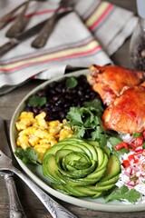 latin american food bowl - rose avocado, rice, salsa, fried banana, spiced baked chicken thighs, black beans, corn, cilantro.