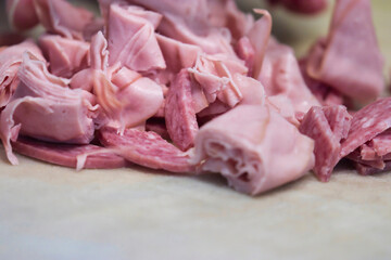 a knife chopping lunch meat for deli salad