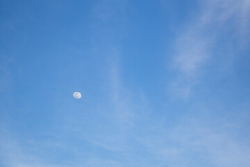 Luna viéndose en cielo azul con nubes
