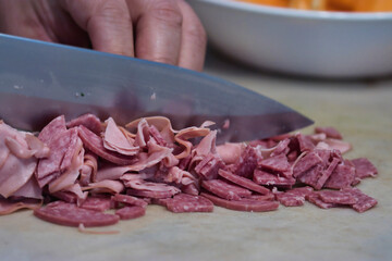 Hand chopping up lunch meat for a salad