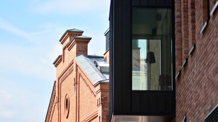 Modern brick and glass facade of the office building.  A contrasting combination of sky and brick texture on a building. Architectural facade of a red brick building..