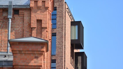 Modern brick and glass facade of the office building.  A contrasting combination of sky and brick texture on a building. Architectural facade of a red brick building..