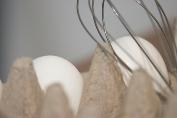 wire wisk on top of eggs in carton