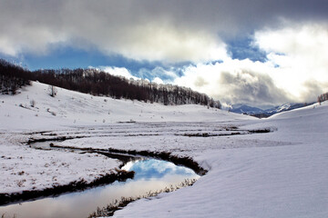 Stream of water running through a snowy field