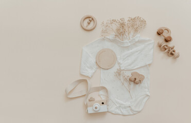 Clothes for baby and newborns: white bodysuits and accessories neutral beige and brown colors. Eco friendly wooden toys on Light background, top view, flat lay. - 429881951