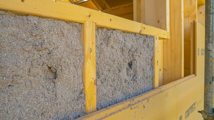 CLOSE UP: Ecofriendly cellulose insulation fills up a frame on a wooden wall.