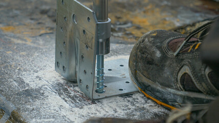 CLOSE UP: Contractor fastens a stainless steel wall carrier into the ground.