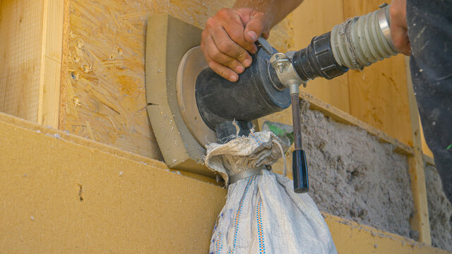 CLOSE UP: Builder uses a blower to insulate the wood wall with recycled paper.
