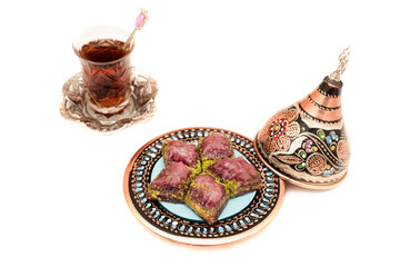 Closeup of traditional Turkish dessert - baklava (violet baklava) isolated on white background. Most popular dessert in Ramadan time (Turkish: Ramazan bayrami). Traditional Turkish tea in glass cup.