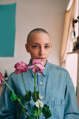 Woman holding flowers and looking to the camera while posing at her flat