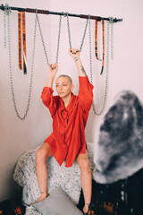Woman wearing red shirt sitting at the fur at home and holding chains