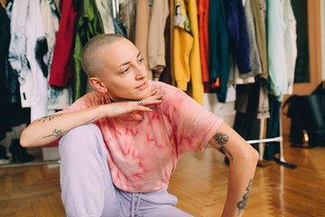 Woman wearing domestic clothes sitting at the floor and looking away