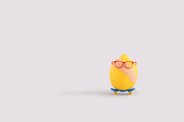 Funny summer concept with lemon wearing eyeglasses and adhesive bandage riding skateboard 
