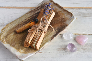 Fototapeta na wymiar A close up image of wooden incense sticks with dried lavender and healing crystals on a white background. 