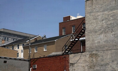 Fototapeta na wymiar Rooftops of Brick and Masonry Buldings with Black Wrought Iron Fire Escape in Daylight